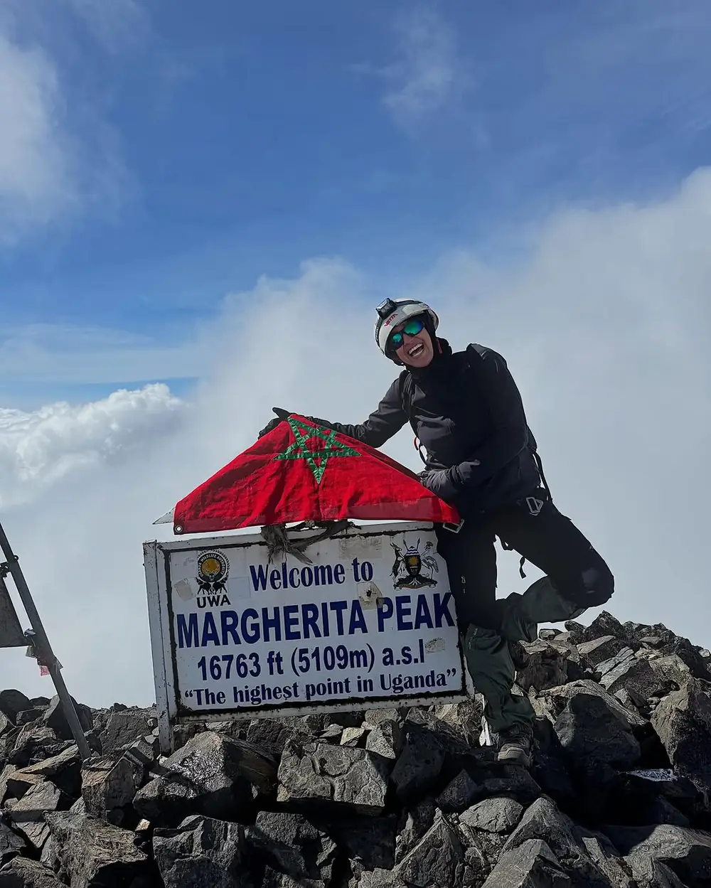 Climber beside the Margherita Peak summit sign in the Rwenzori Mountains