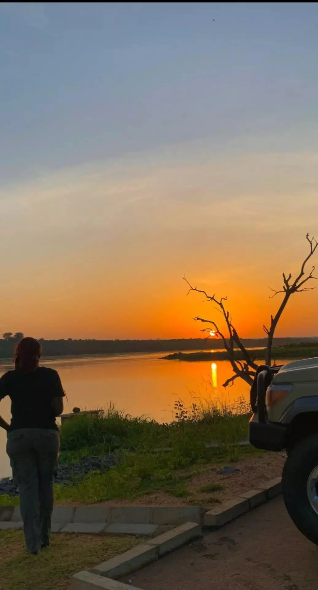 Safari vehicle beside water at sunset in Uganda